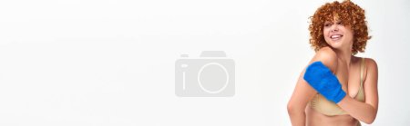 Foto de Alegre pelirroja más tamaño mujer con paños manoplas lavado curvas cuerpo en blanco, bandera horizontal - Imagen libre de derechos