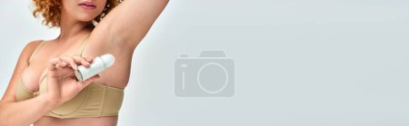 Foto de Vista recortada de la mujer con curvas en lencería aplicando desodorante roll-on en la axila, bandera horizontal - Imagen libre de derechos