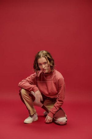 Photo for Self-expression, stylish gen z girl in patchwork pants and cropped long sleeve on red backdrop - Royalty Free Image