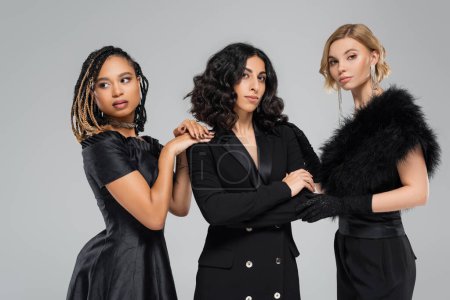 Téléchargez les photos : Trois charmantes amies multiculturelles en tenue noire élégante sur gris, beauté diverse - en image libre de droit
