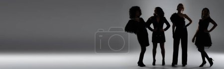 Photo for Black silhouettes of multiethnic girlfriends in elegant attire with hands on hips on grey, banner - Royalty Free Image