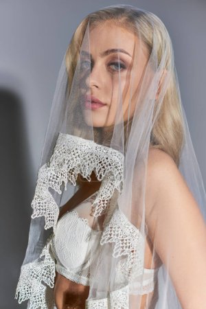 vertikale Aufnahme einer attraktiven sexy Frau in weißen verführerischen Dessous mit Schleier, die in die Kamera schaut