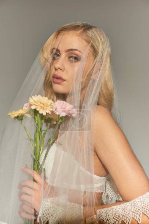 vertikale Aufnahme eines attraktiven jungen weiblichen Models, das mit Blumenstrauß posiert und in die Kamera blickt