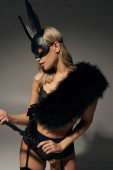 vertical shot of alluring woman in black lingerie and faux fur with rabbit mask holding bdsm whip Tank Top #679261662
