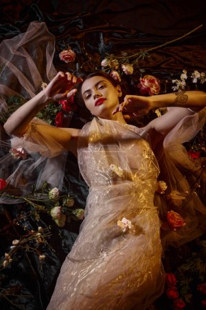 feminine elegance, sensual woman in romantic transparent dress lying among beautiful flowers