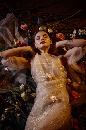 feminine Eleganz, sinnliche junge Frau in romantischem transparentem Kleid zwischen schönen Blumen liegend