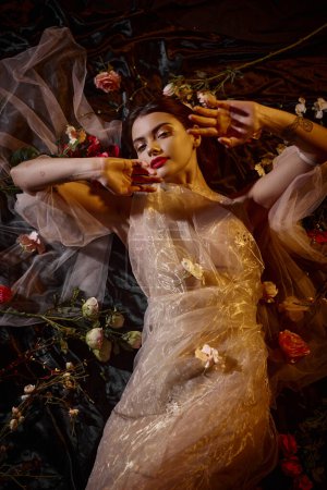 weibliche Eleganz, sinnliche junge Frau in transparentem Kleid zwischen schönen Blumen liegend, Draufsicht
