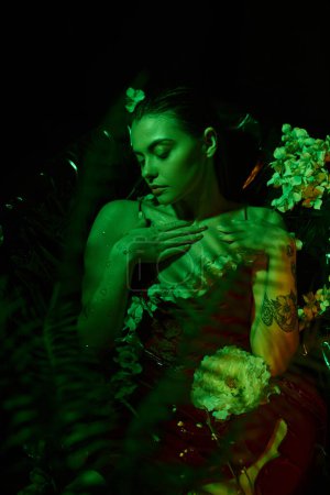 grünes Licht, charmante junge Frau mit nassen Haaren, die wegschaut und zwischen Blumen posiert, Eleganz