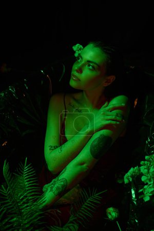 grünes Licht, attraktive junge Frau mit nassen Haaren posiert in der Badewanne inmitten von Blumen, nasser Körper