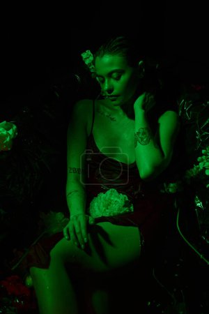 Grünes Licht, Draufsicht auf attraktive junge Frau mit nassen Haaren, die zwischen Blumen in der Badewanne posiert