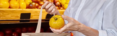 vista recortada de la mujer poniendo tomate amarillo en la bolsa de compras, mientras que en la tienda de comestibles, pancarta
