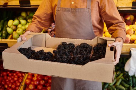 Photo for Cropped view of mature salesman holding huge amount of fresh juicy blackberries at grocery store - Royalty Free Image