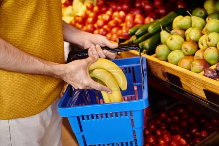 Foto de Vista recortada del cliente macho maduro poniendo plátanos frescos en la cesta de la compra en la tienda de comestibles - Imagen libre de derechos