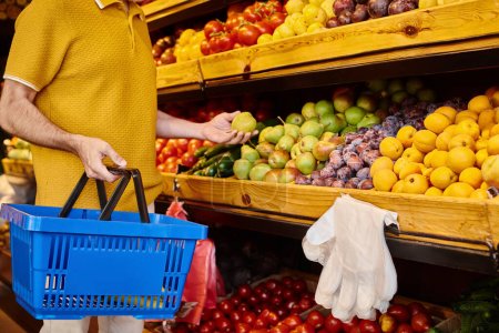 cropped view of mature male customer in casual attire picking fresh fruits at grocery store