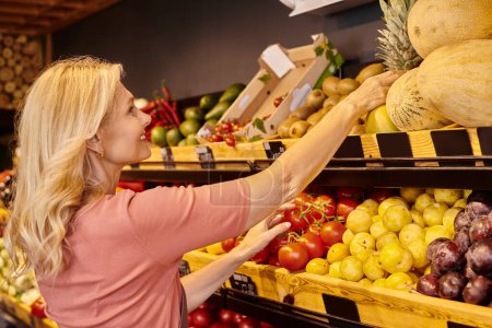 Ältere fröhliche Verkäufer lächeln, während sie neben dem Lebensmittelstand mit frischem Obst und Gemüse arbeiten
