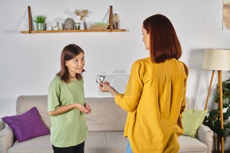 madre mostrando condón a confusa hija adolescente durante la conversación en casa, educación sexual