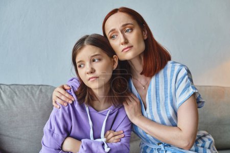Photo for Worried mother embracing and calming upset teenage daughter at home in living room, support and care - Royalty Free Image