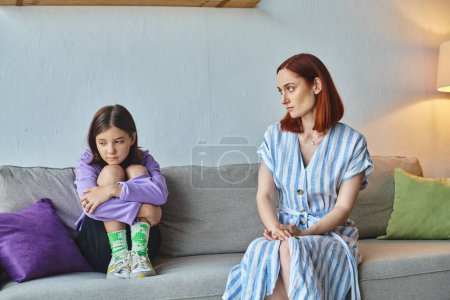 Photo for Worried mother looking at depressed teenage daughter on couch in living room, supportive parent - Royalty Free Image