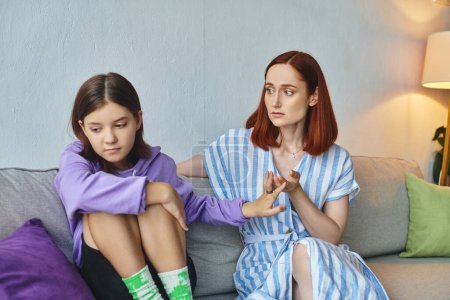 fürsorgliche Mutter im Gespräch mit frustrierter Teenager-Tochter, die zu Hause auf der Couch sitzt, Liebe und Unterstützung