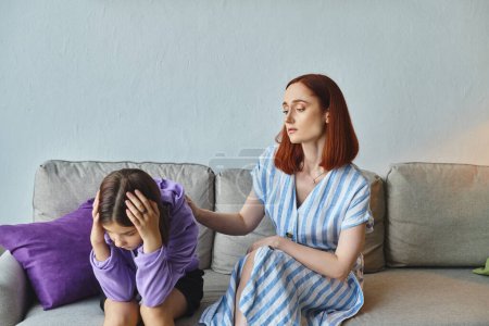 madre preocupada calmando deprimida hija adolescente sentada con la cabeza inclinada en el sofá en casa, apoyo