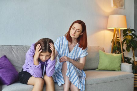besorgte Mutter beruhigt depressive Teenager-Tochter sitzt mit gesenktem Kopf auf Couch zu Hause, Unterstützung
