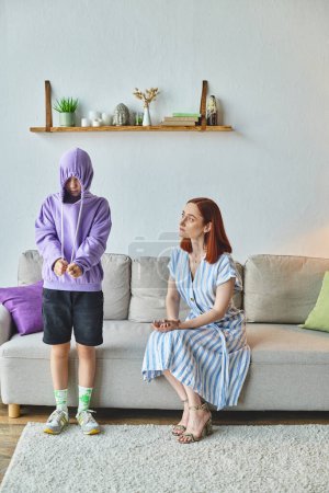 Foto de Mujer preocupada y molesta hablando con la hija ofendida escondida en el capó en la sala de estar, brecha de generación - Imagen libre de derechos