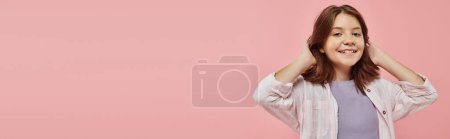 Foto de Alegre y elegante chica preadolescente con el pelo brillante saludable sonriendo a la cámara en el telón de fondo rosa, bandera - Imagen libre de derechos