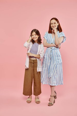 Photo for Cheerful mother and preteen daughter in stylish casual clothes posing and smiling at camera on pink - Royalty Free Image