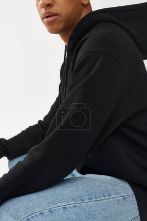 modelo masculino afroamericano de moda en sudadera con capucha negra casual y jeans, espacio de copia para la publicidad