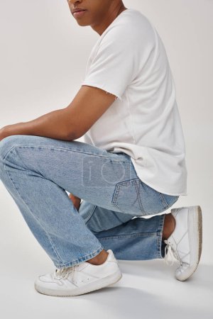 stylish african american man in trendy casual jeans and white t-shirt, copy space for advertising