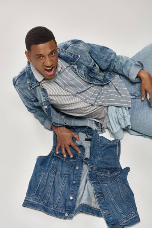 good looking african american man in stylish denim outfit posing in motion, fashion concept