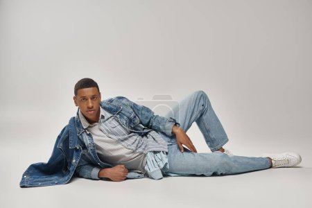 attraktive emotionale afrikanisch-amerikanische Mann in stilvollem Jeans-Outfit posiert in Bewegung, Modekonzept