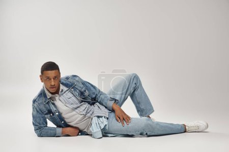 attractive emotional african american man in stylish denim outfit posing in motion, fashion concept