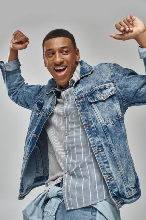 attraktive emotionale afrikanisch-amerikanische Mann in stilvollem Jeans-Outfit posiert in Bewegung, Modekonzept