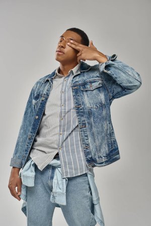 attraktive emotionale afrikanisch-amerikanische Mann in stilvollem Jeans-Outfit gestikuliert lebhaft, Modekonzept