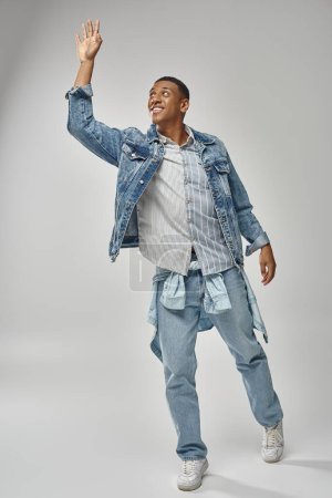 attraktive emotionale afrikanisch-amerikanische Mann in stilvollem Jeans-Outfit gestikuliert lebhaft, Modekonzept