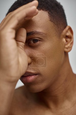 primer plano de atractivo hombre afroamericano atractivo con la mano en frente de la cara, concepto de moda