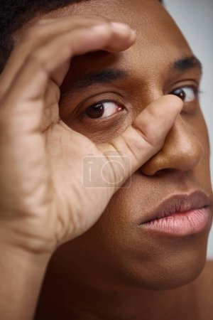 close up of handsome appealing african american man with hand in front of face, fashion concept