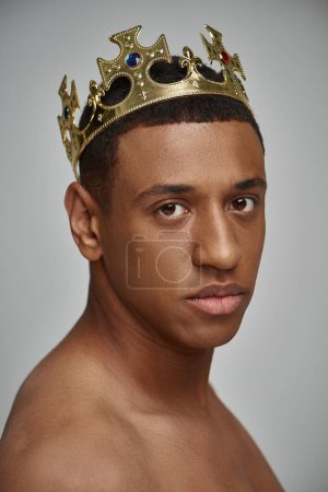 portrait of appealing african american male model in golden crown posing topless, fashion concept