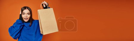 Foto de Pancarta de mujer emocionada en traje de otoño sosteniendo bolsa de compras con letras de viernes negro en naranja - Imagen libre de derechos