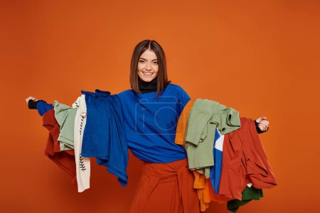 happy woman with brunette short hair holding colorful autumnal clothes,  black friday concept