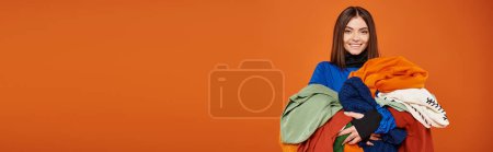 banner of joyful woman with brunette hair holding colorful autumnal clothes,  black friday concept