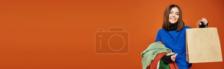 Photo for Banner of happy woman holding pile of colorful autumnal clothes and shopping bag on black friday - Royalty Free Image