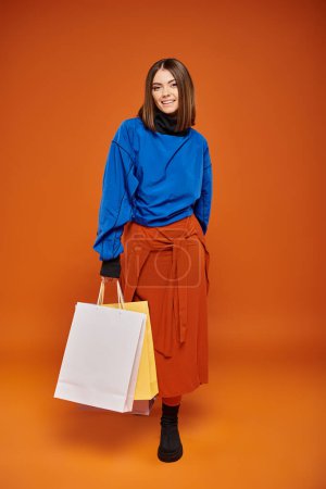 lebensfrohe Frau in stylischer Herbstkleidung mit Einkaufstüten am schwarzen Freitag