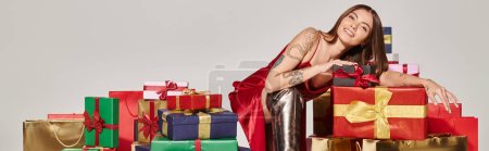 beautiful young woman posing near pile of presents looking at camera, holiday gifts concept, banner