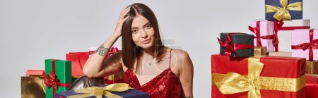 Photo for Attractive woman with tattoos posing near presents on ecru backdrop, holiday gifts concept, banner - Royalty Free Image