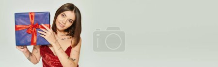 Téléchargez les photos : Heureuse dame en robe rouge avec accessoires regardant appareil photo tenant présent, cadeaux de vacances, bannière - en image libre de droit