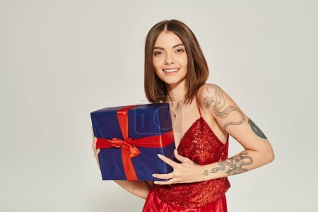 attraktive junge Dame hält Geschenk in den Händen und lächelt in die Kamera, Konzept für Weihnachtsgeschenke
