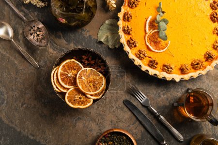Erntedank-Kulisse mit leckerem Kürbiskuchen, Vintage-Besteck und Orangenscheiben auf Steintisch