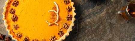 Foto de Delicioso símbolo de acción de gracias, pastel de calabaza con nueces y rodajas de naranja en el fondo de piedra, bandera - Imagen libre de derechos